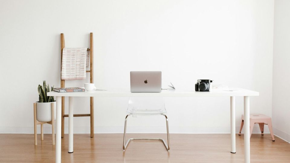 Heller, aufgeräumter Arbeitsplatz mit Schreibtisch und Laptop