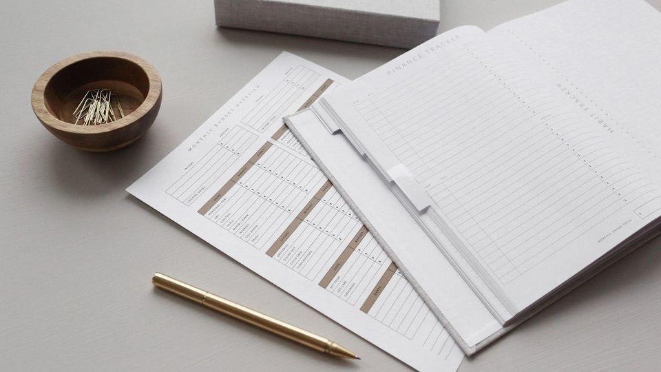 Aufgeschlagener Kalender mit Formularen und Stift auf einem hellen Tisch