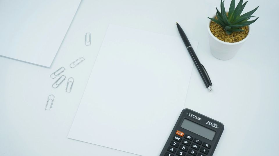 Calculator, pen and paper on a bright desk
