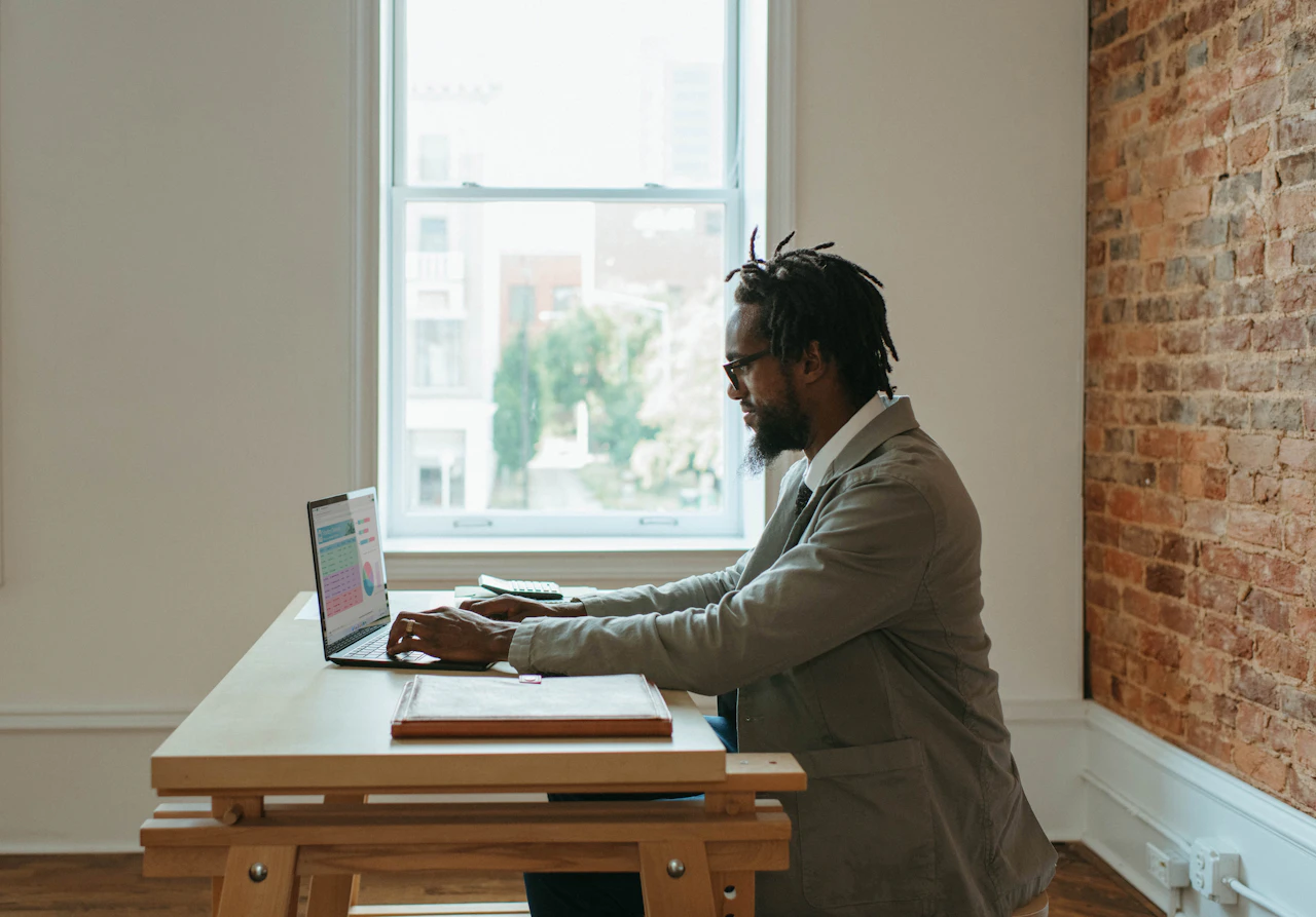 Person arbeitet mit Laptop und Unterlagen am Schreibtisch