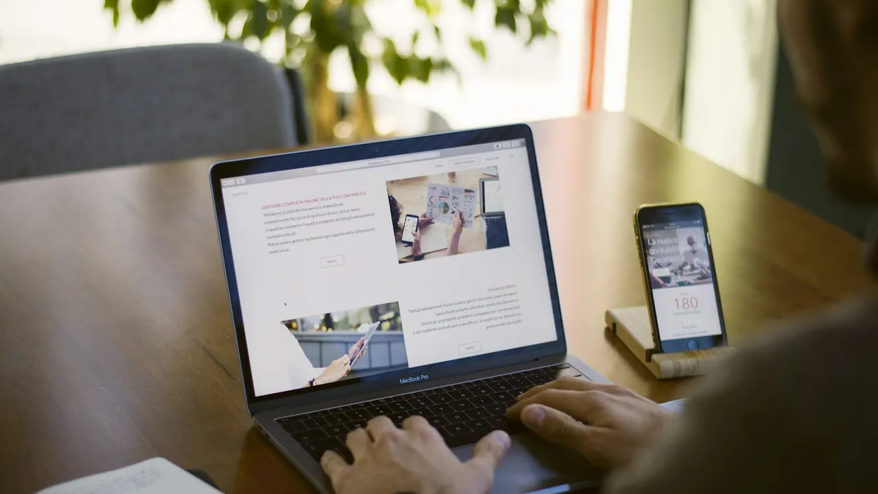 Person working on a laptop with a smartphone beside it