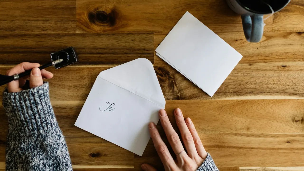 Hands opening an envelope on a wooden desk
